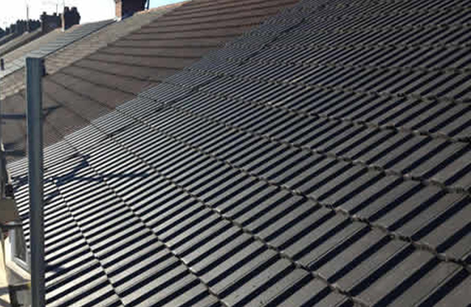 Dark gray tile roof of a residential building, with lines of tiles in diagonal pattern.