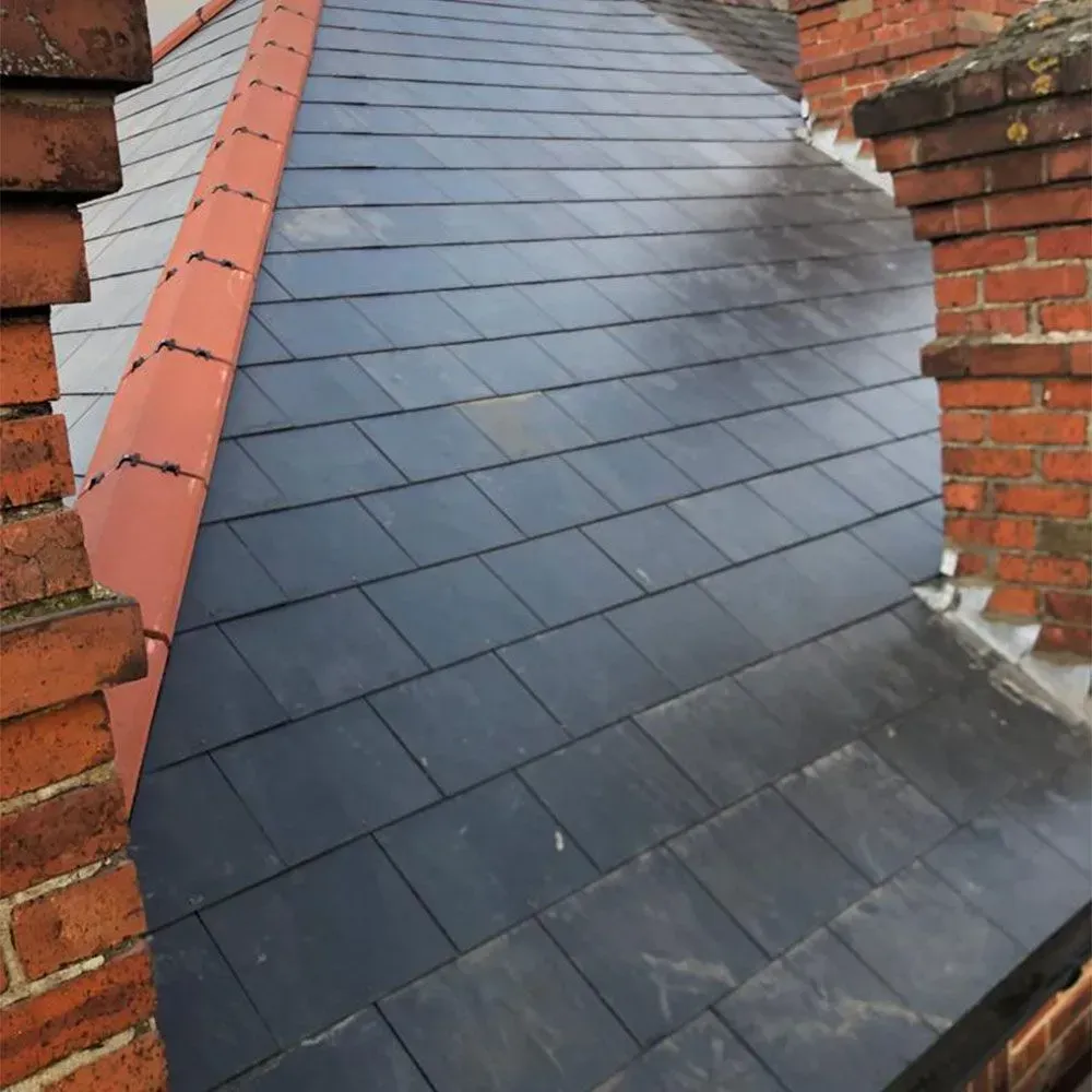Slate roof with red ridge cap and brick chimneys.