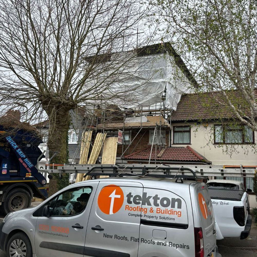 House with scaffolding and tarp for roof repairs; Tekton van parked in front.
