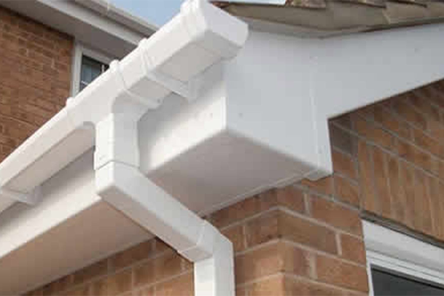 White gutters and downspout on a brick building's corner.