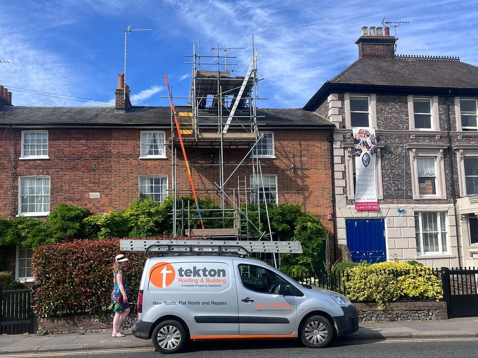 Scaffolding erected on a brick building with a Tekton van parked in front.