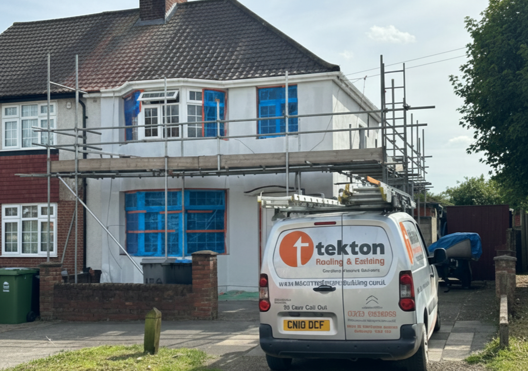House undergoing renovation with scaffolding and a Tekton van parked in front.