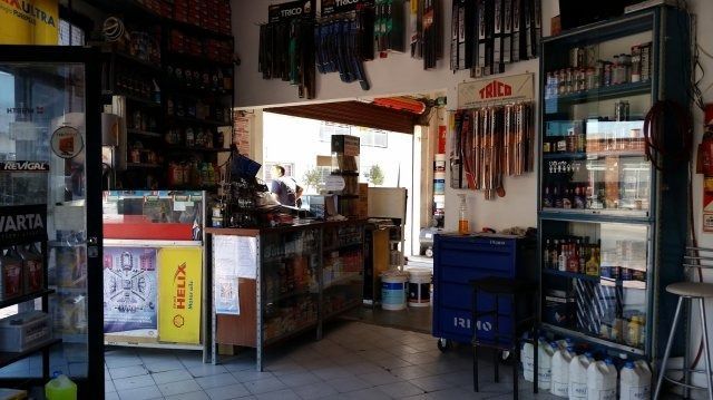 Interior de una tienda de conveniencia con bebidas, aperitivos y una vitrina refrigerada.
