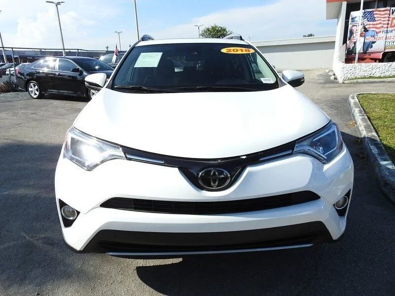A white Toyota RAV4 parked on an asphalt lot on a sunny day.