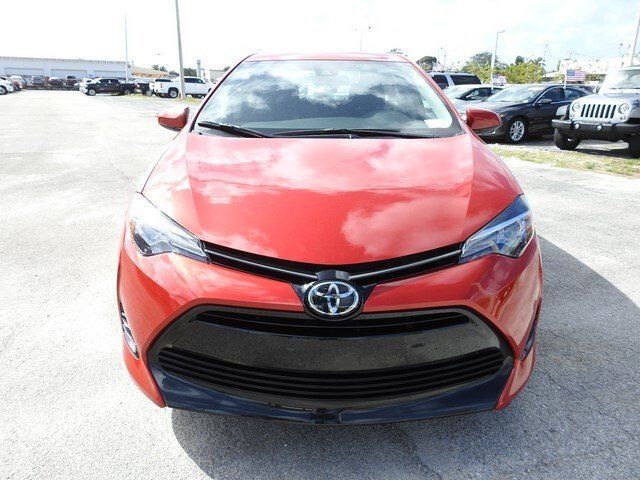 A front view of a red Toyota Corolla sedan parked on an outdoor car dealership lot.