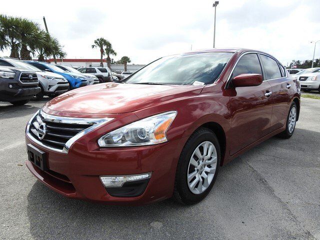 A dark red Nissan Altima sedan parked on an asphalt car lot.