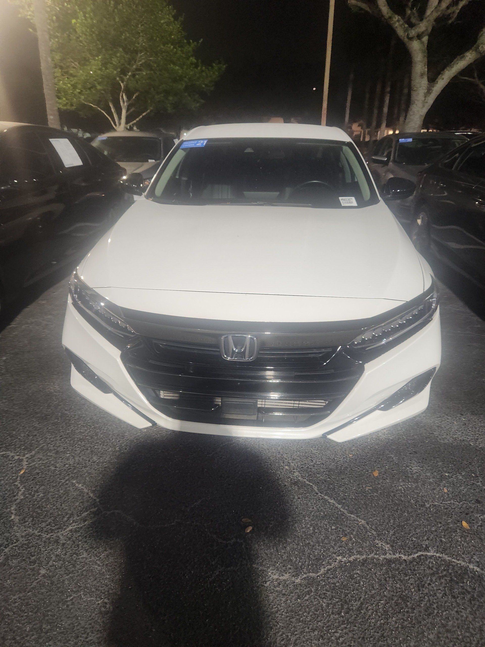 A white Honda Accord parked in a lot at night.