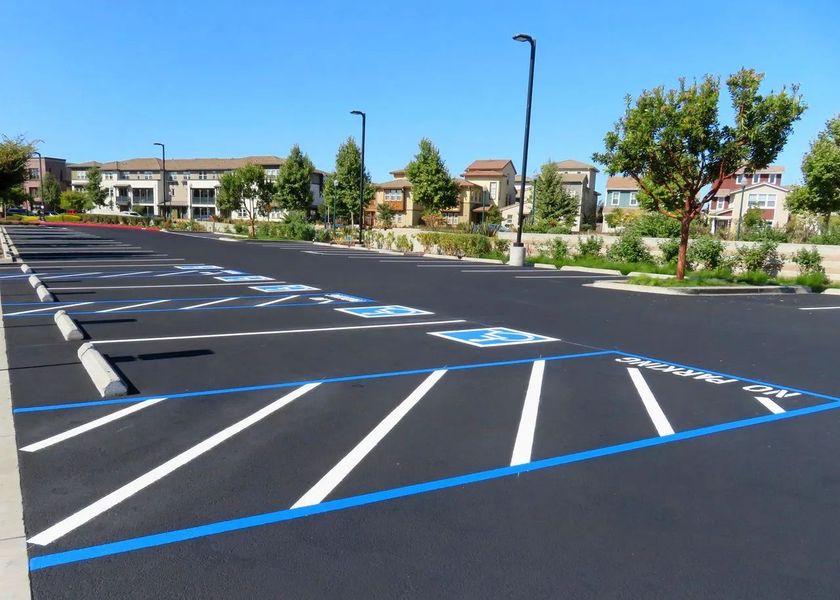 Empty accessible parking lot with blue-striped spaces and apartment buildings in the background