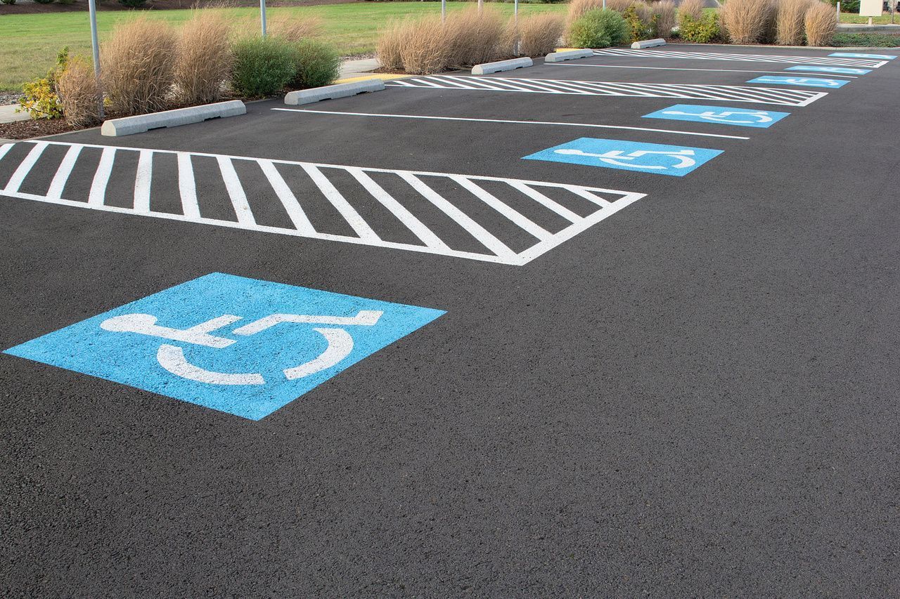 Accessible parking spaces painted blue in a parking lot with striped access aisle