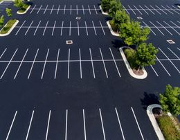 Empty parking lot with white lines and small trees in planter islands