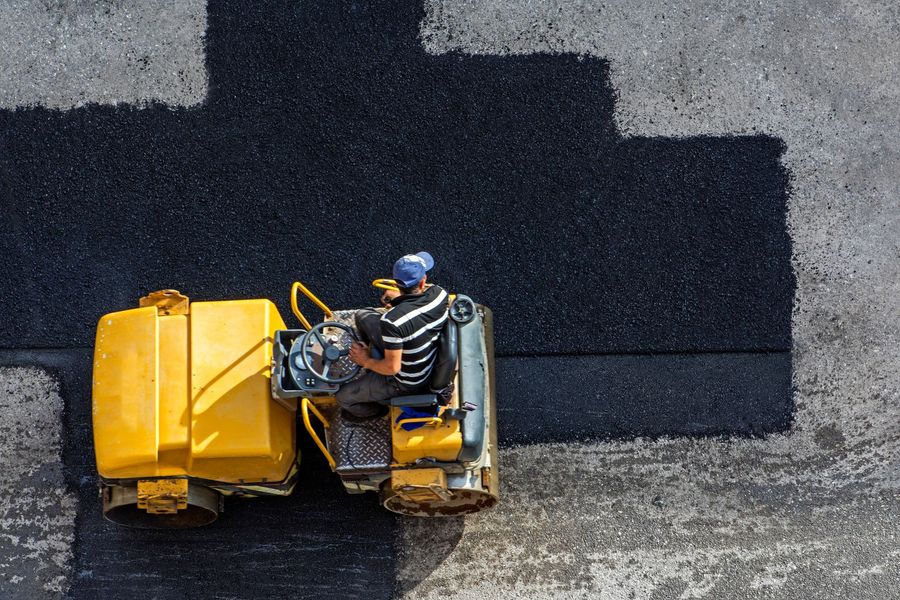 Yellow road roller paving black asphalt on a street