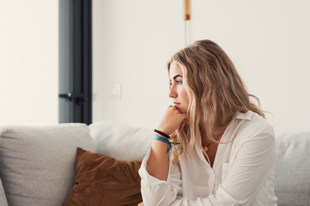 Group therapy session: A woman comforts a distressed man, hand on his shoulder. Several diverse individuals sit in a circle in a brightly lit room.