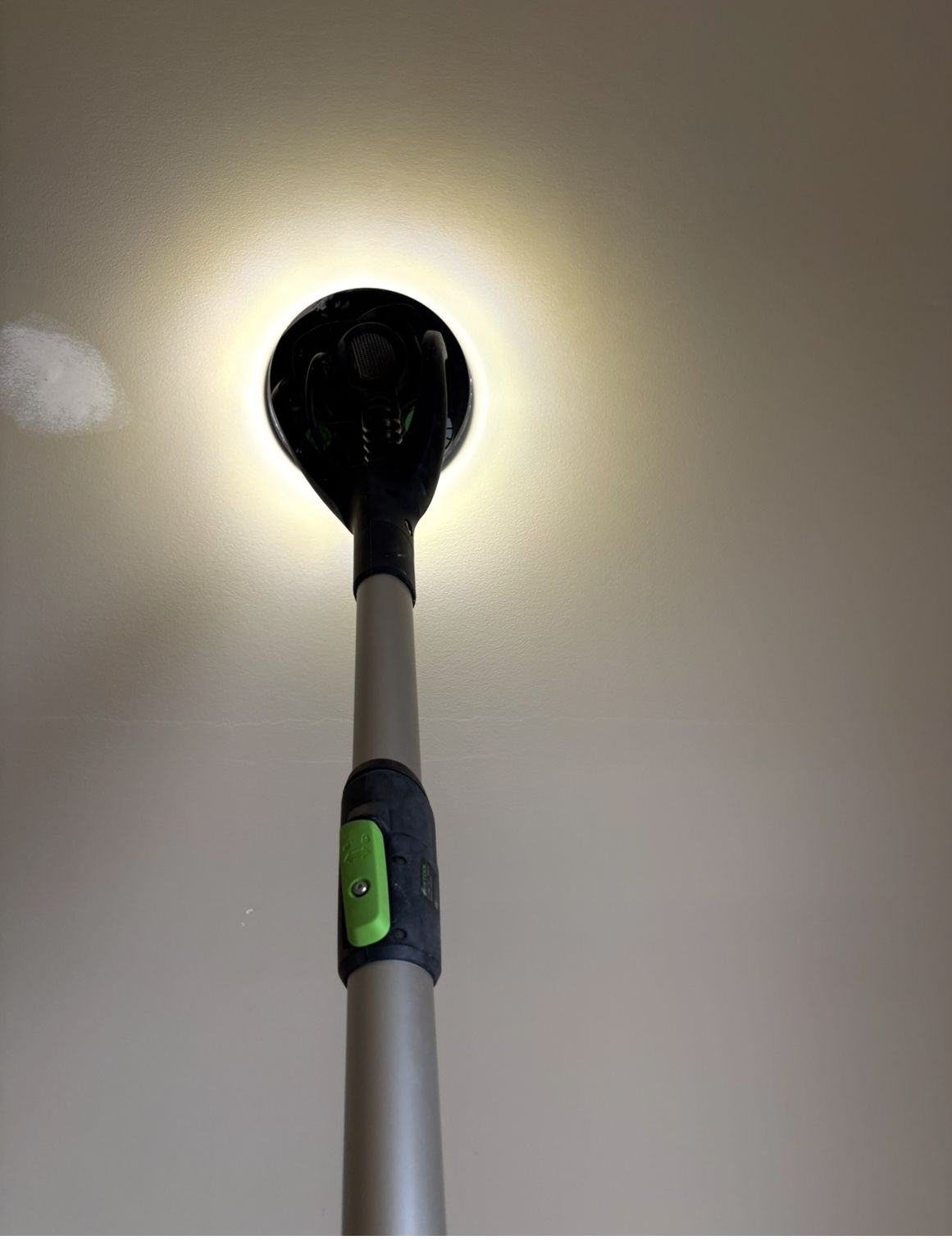 Black-and-white floor lamp viewed from below, lit against a plain wall.