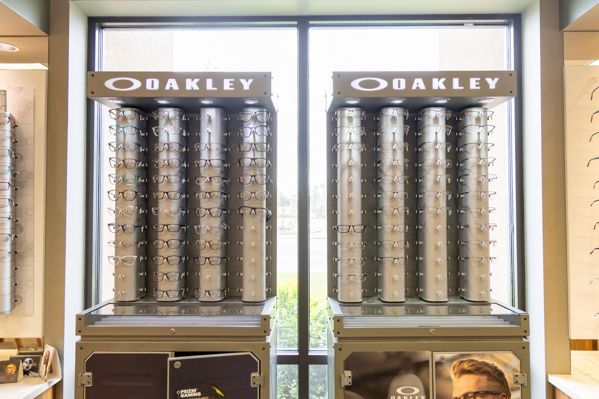 Oakley sunglasses display racks in a store window with bright backlit signage