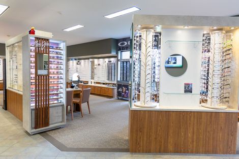 Eyeglass store interior with display cases, rows of frames, and a wood counter