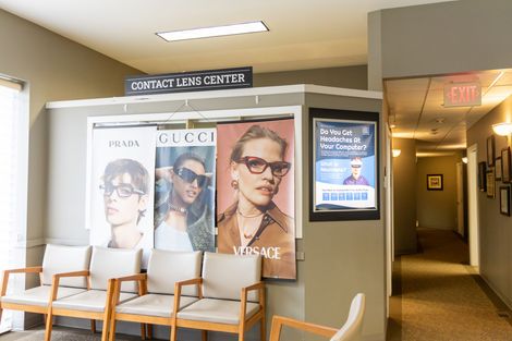 Optical clinic waiting area with chairs, eye exam posters, and a hallway with exit sign