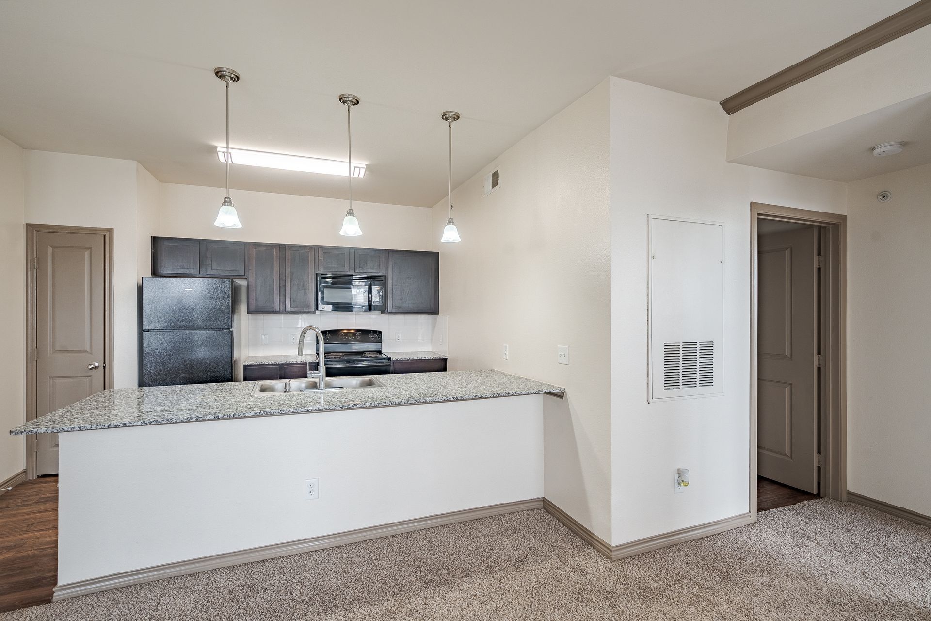 Open-concept kitchen with granite island and stainless-steel appliances.
