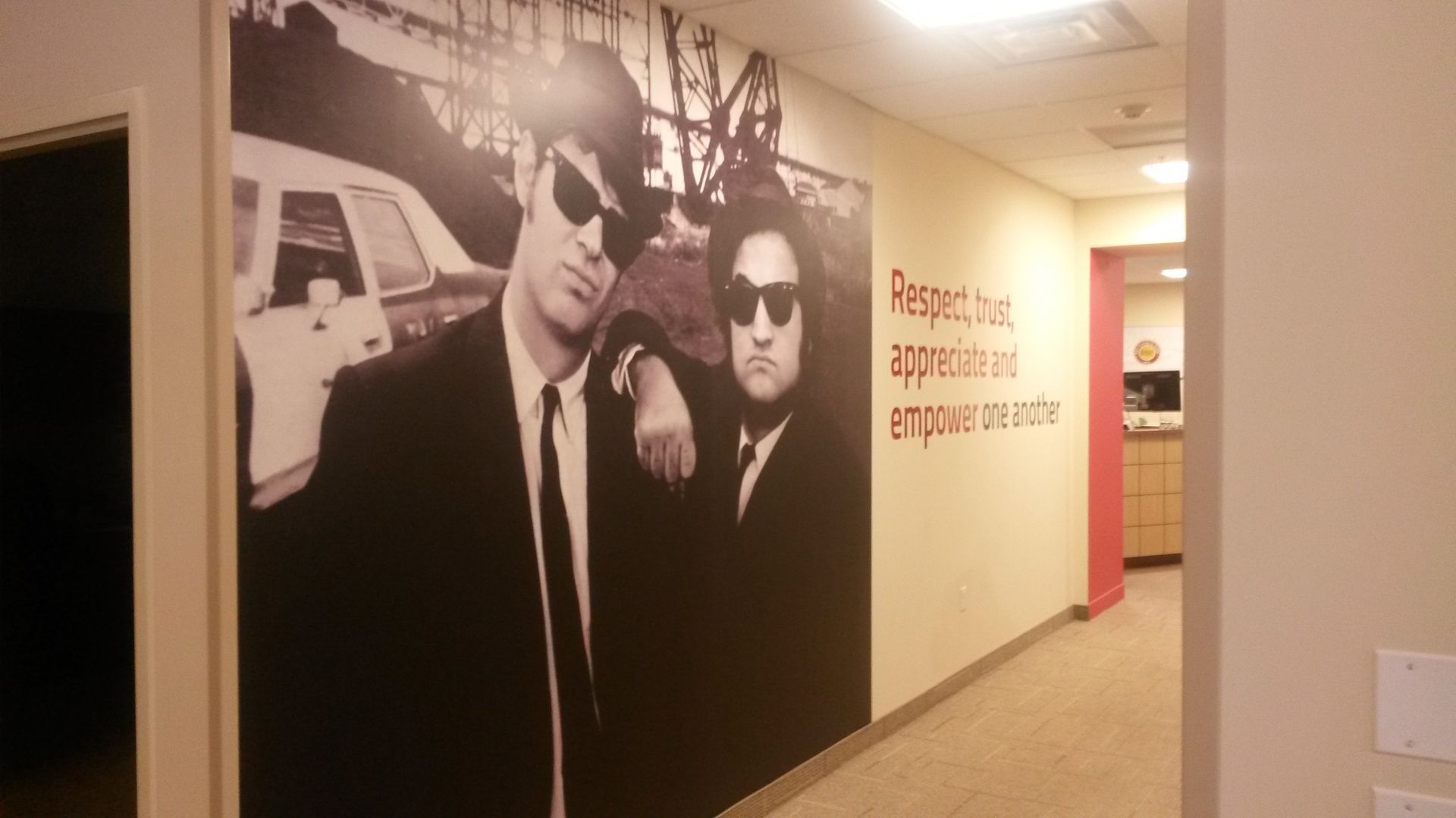 Hallway with a large wall mural of two men in black suits and sunglasses, plus red text on the right wall