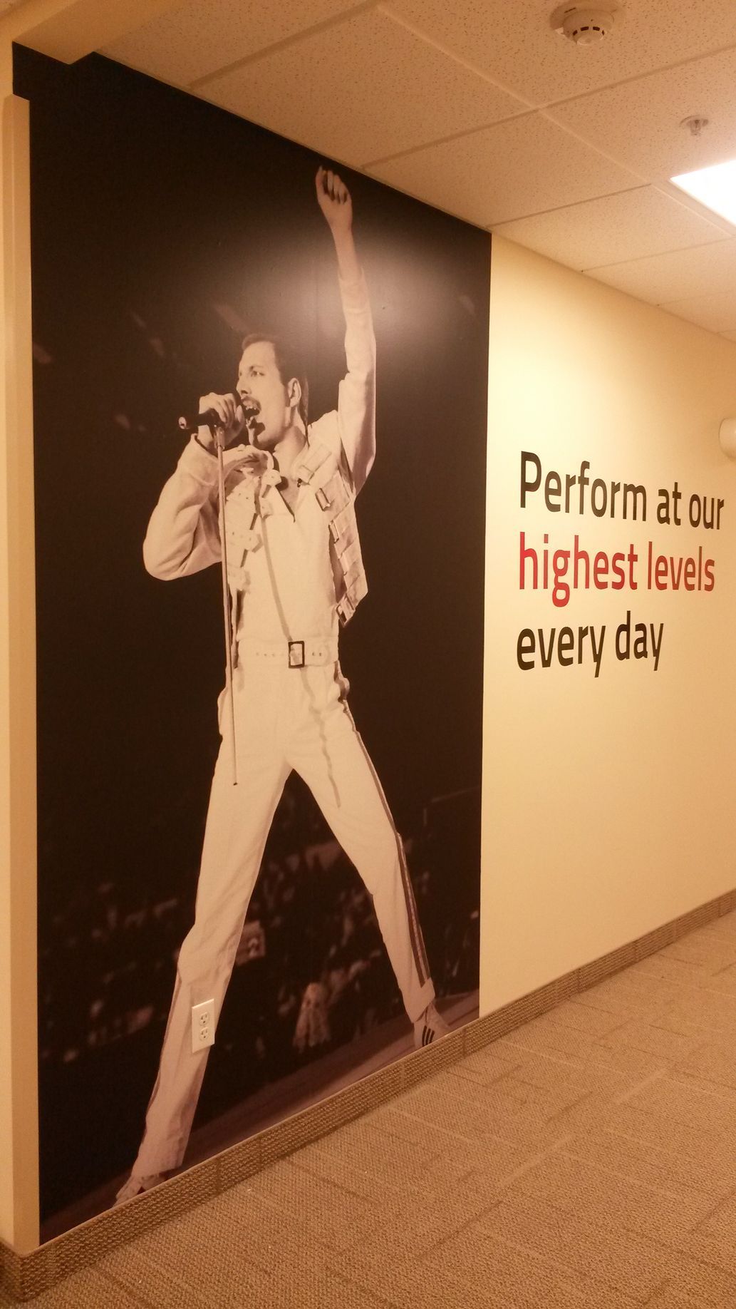 Hallway wall mural of a singer onstage beside the slogan “Perform at our highest lives every day”