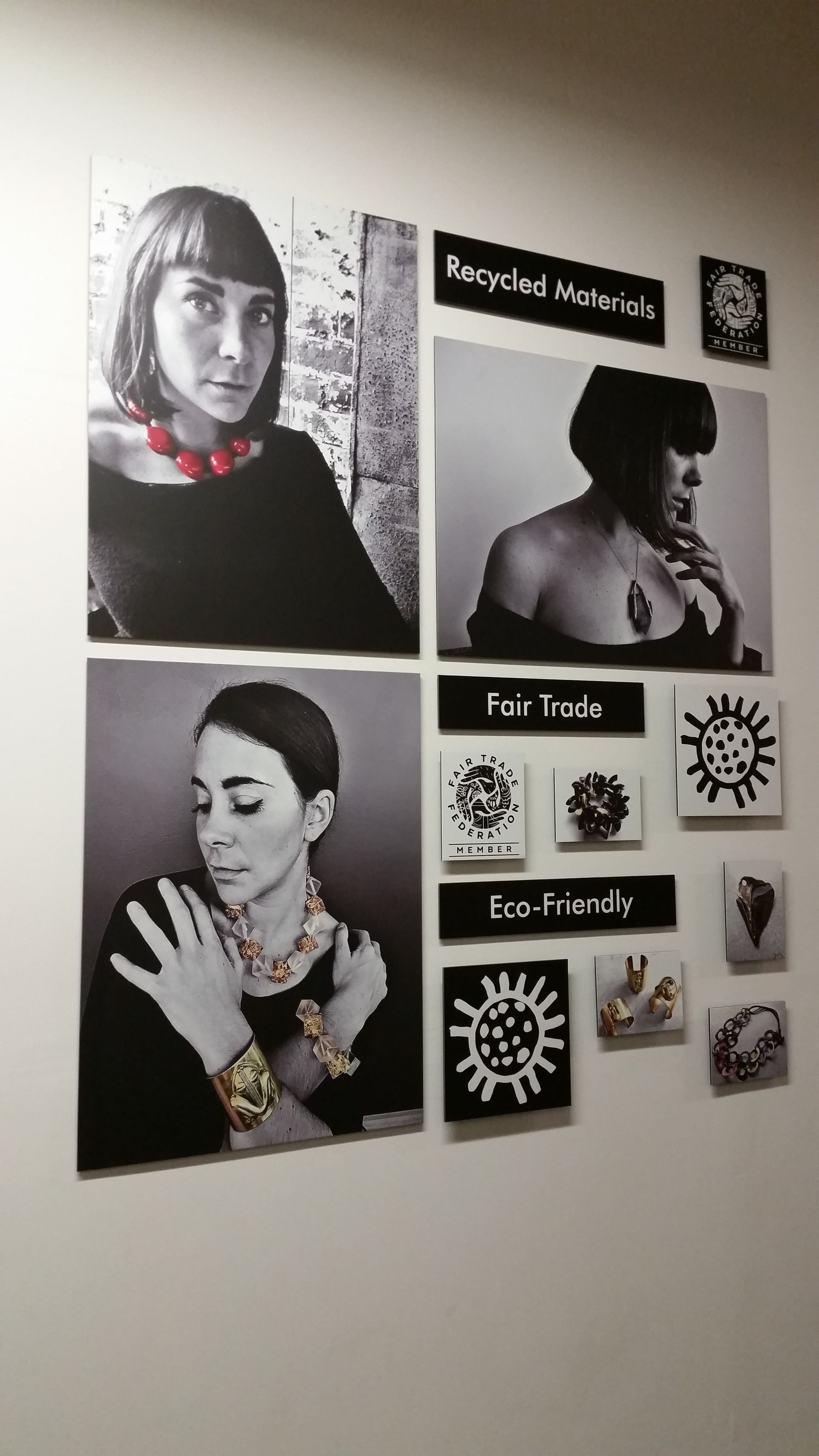Wall display of black-and-white portraits and floral prints, with labels and a small clock on a beige wall