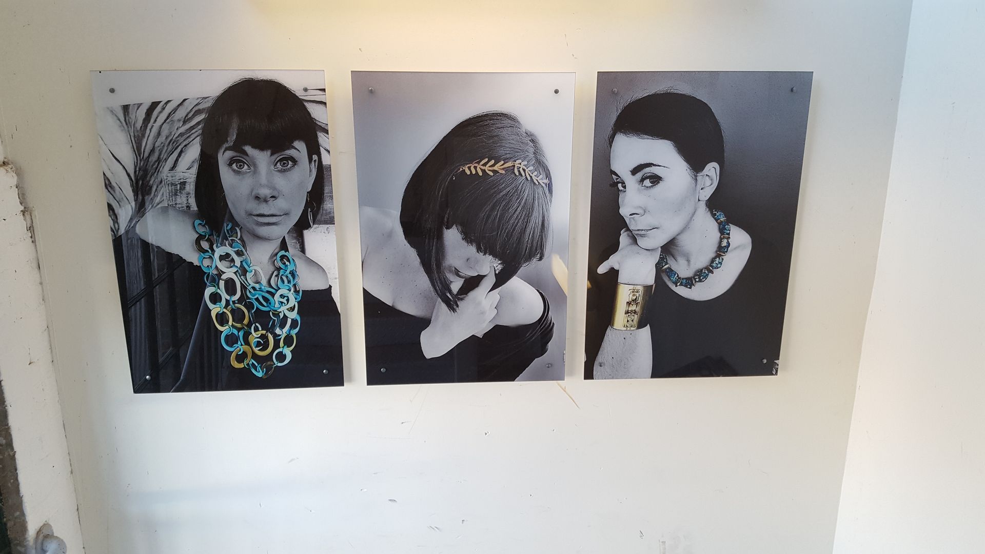 Three black-and-white portrait prints of people displayed side by side on a wall.