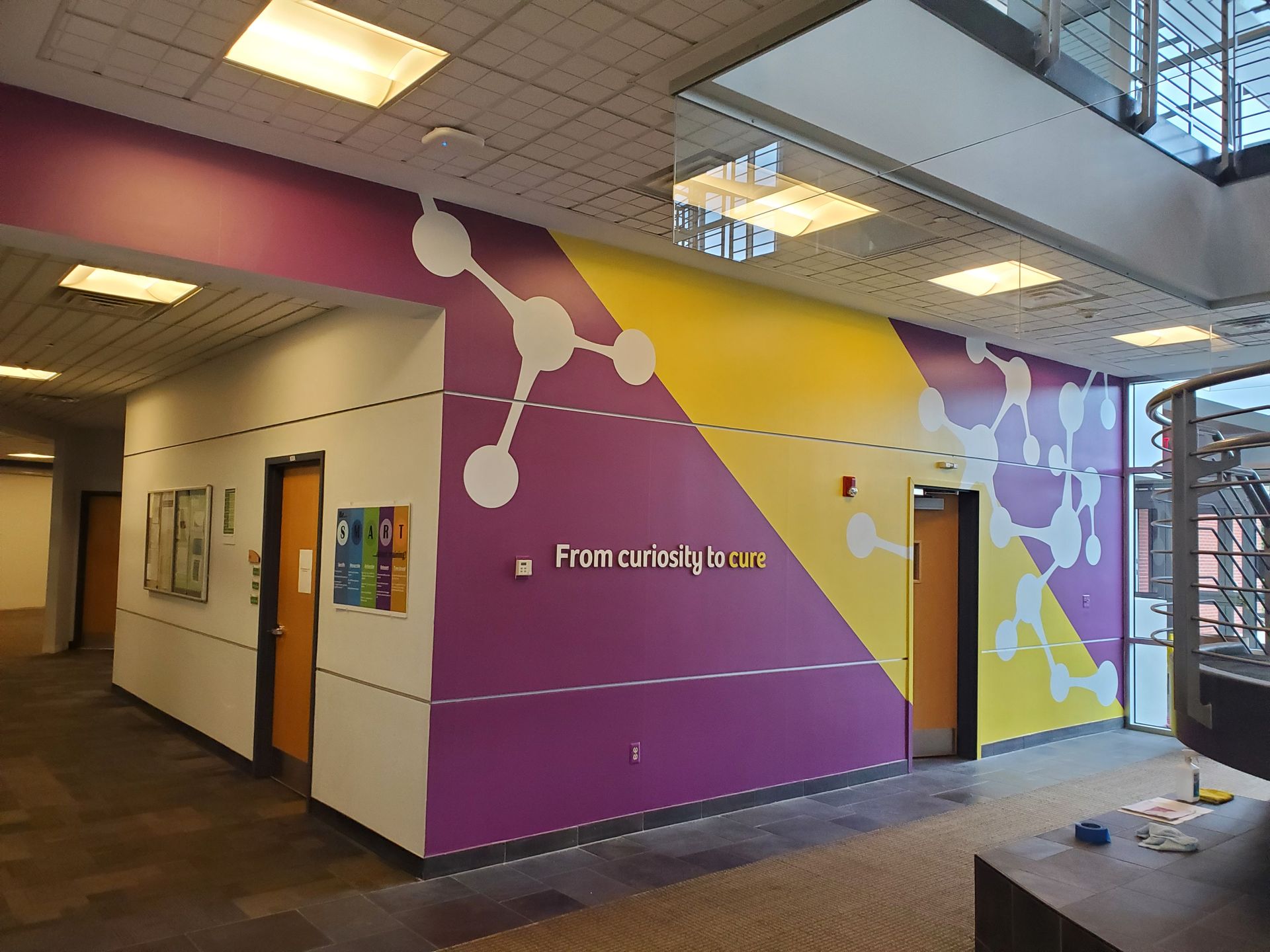 Colorful hallway mural with geometric shapes and a doorway in a building interior