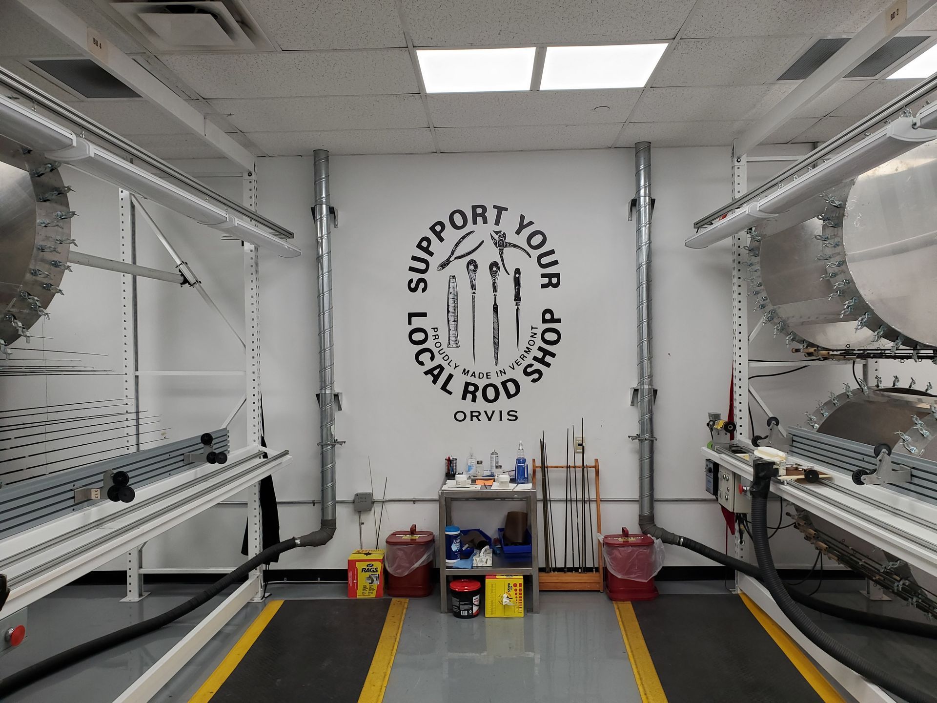 Interior of a clean white industrial chamber with large cylindrical machinery and a “Support Your Local Rods” wall logo.