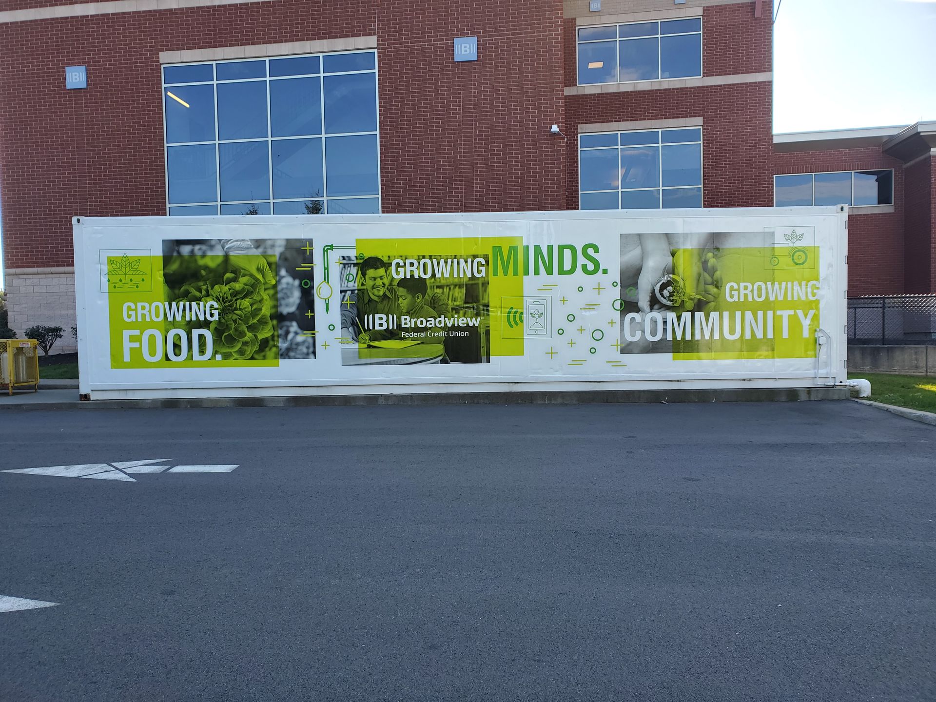 White banner on a brick building reads “Growing Food, Minds, Community.”