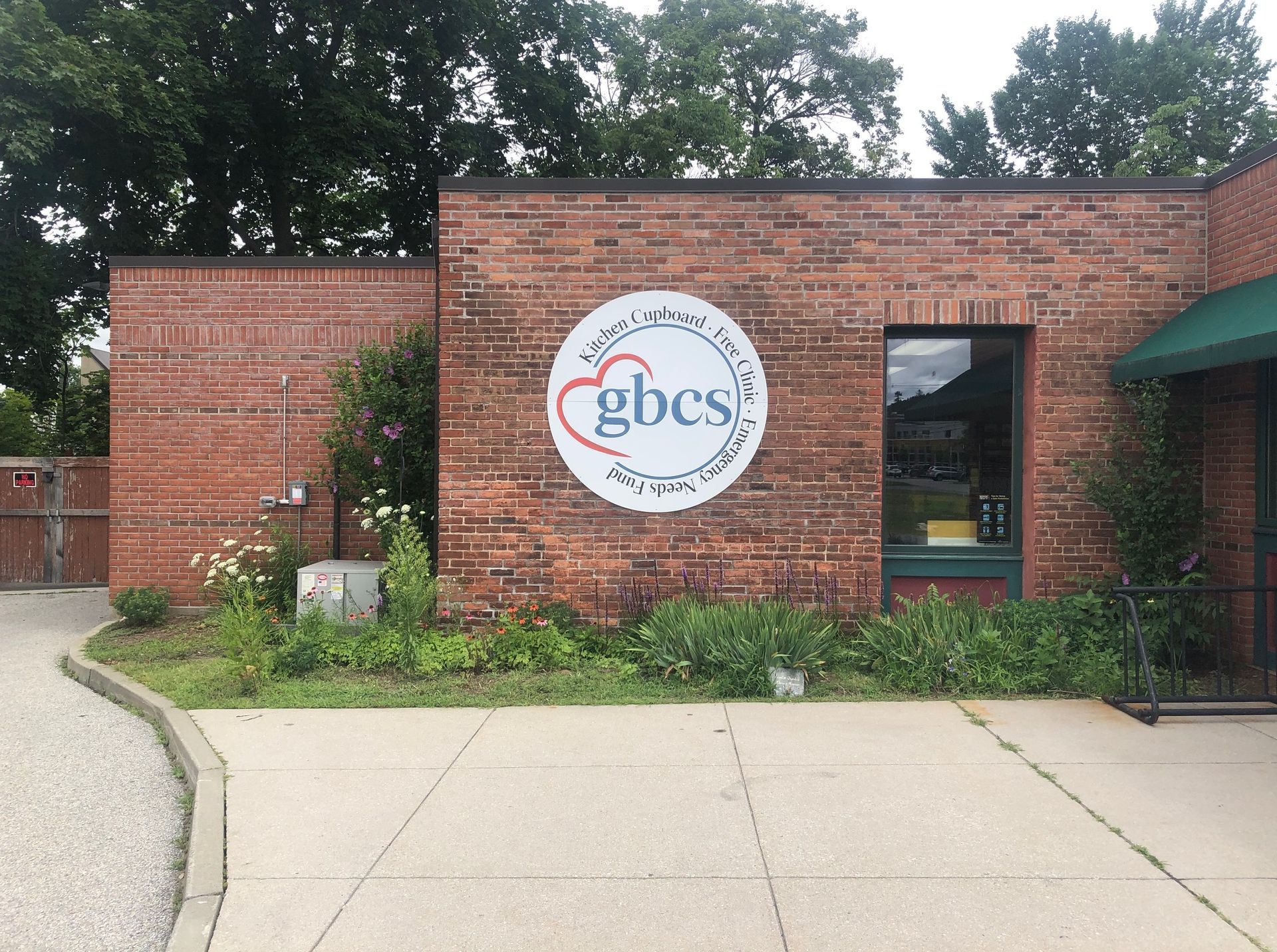 Brick building entrance with a circular logo, "gbcs", and a window.