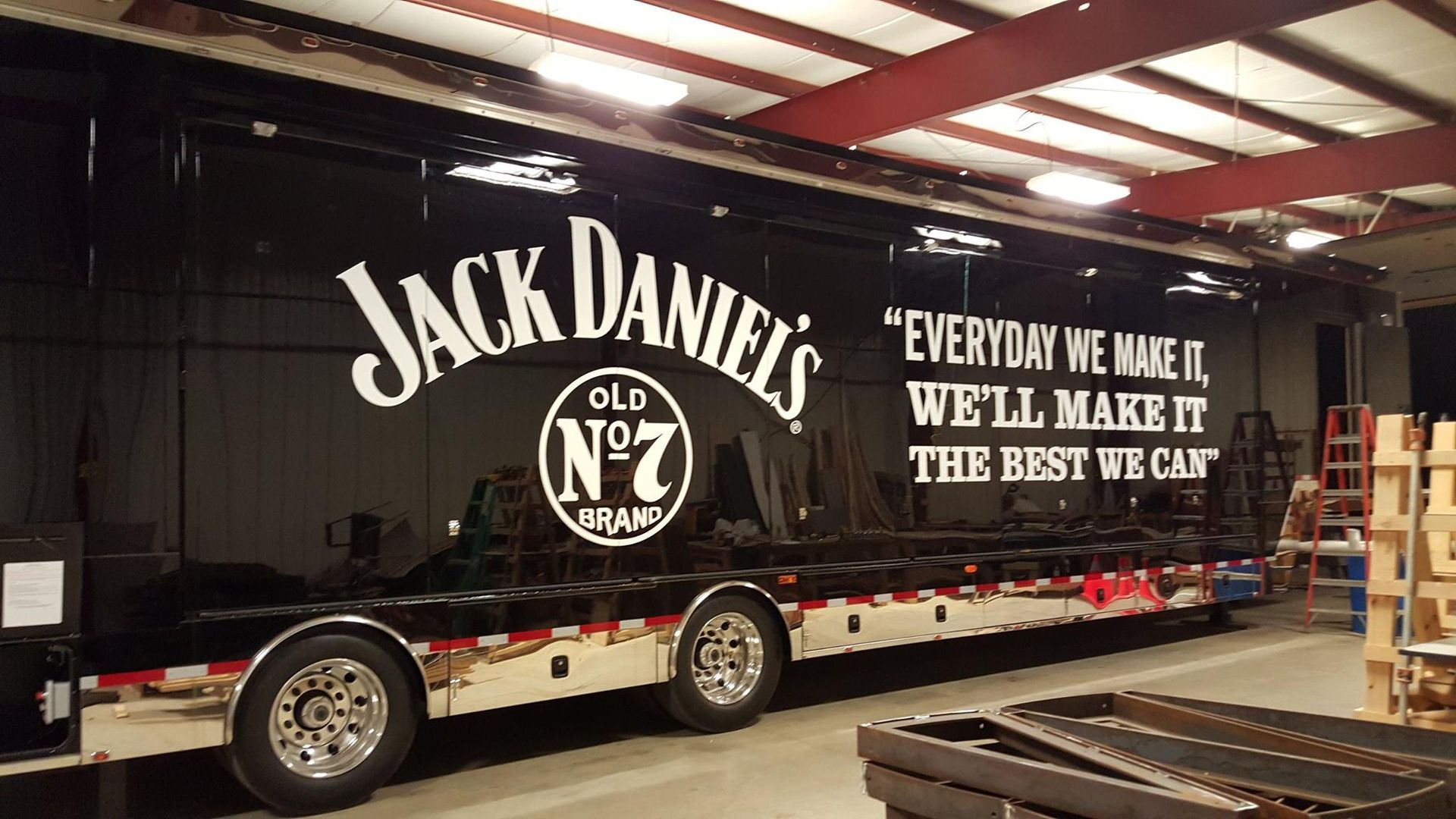 Black trailer with Jack Daniel's logo and quote inside a warehouse.