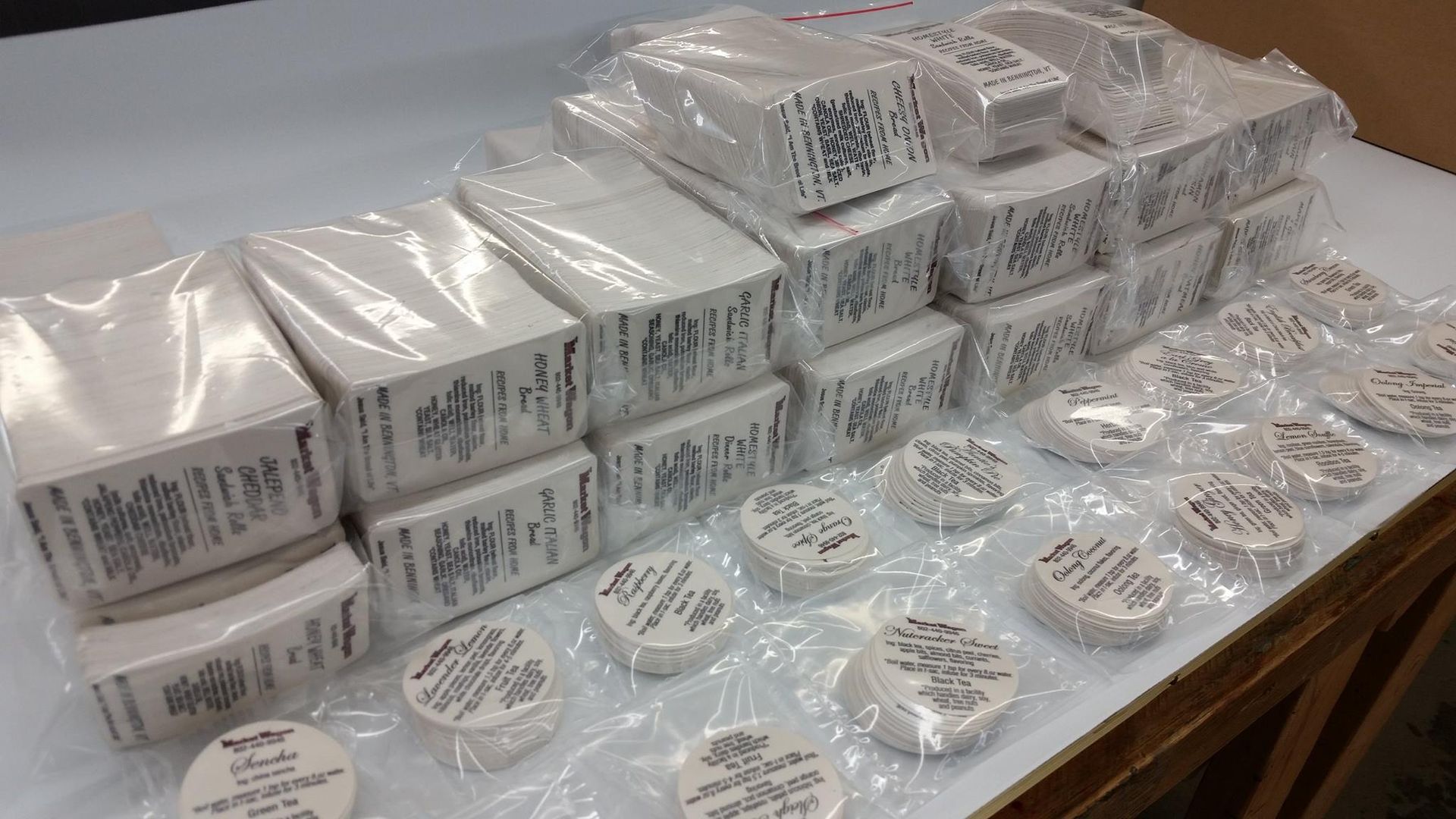 Stacks of packaged white soap bars and round soaps on a table.