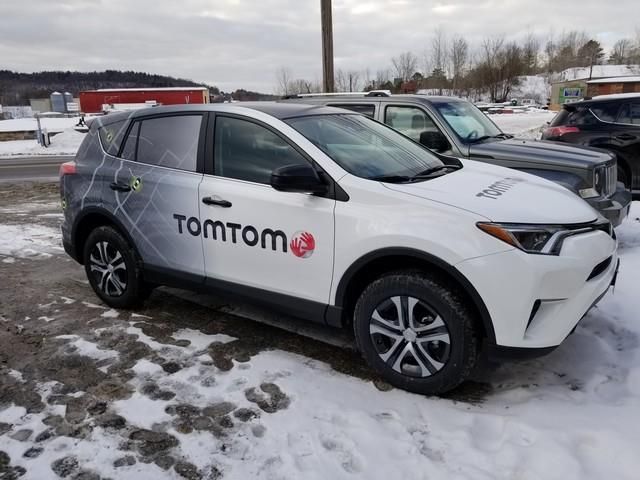 White and black TomTom branded SUV parked in snowy conditions.