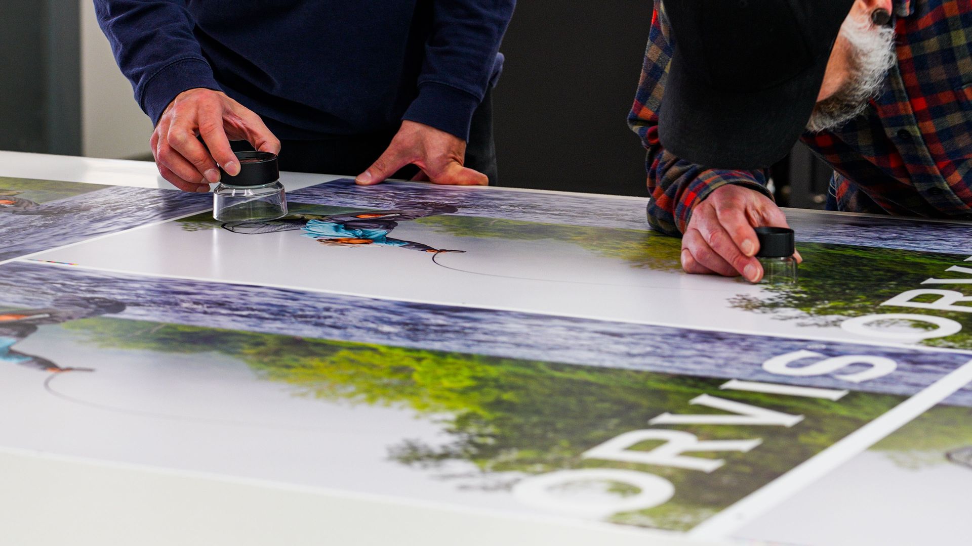 Two people smoothing the surface of a large printed graphic, possibly an advertisement.