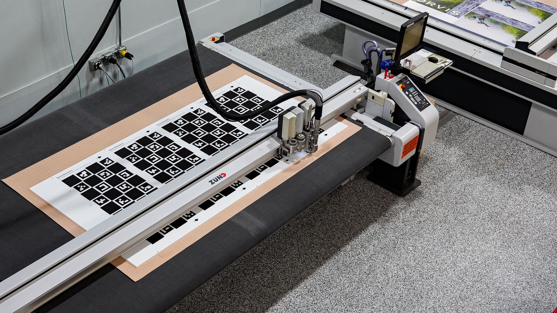 Large-format cutting machine cutting intricate patterns from a printed sheet.