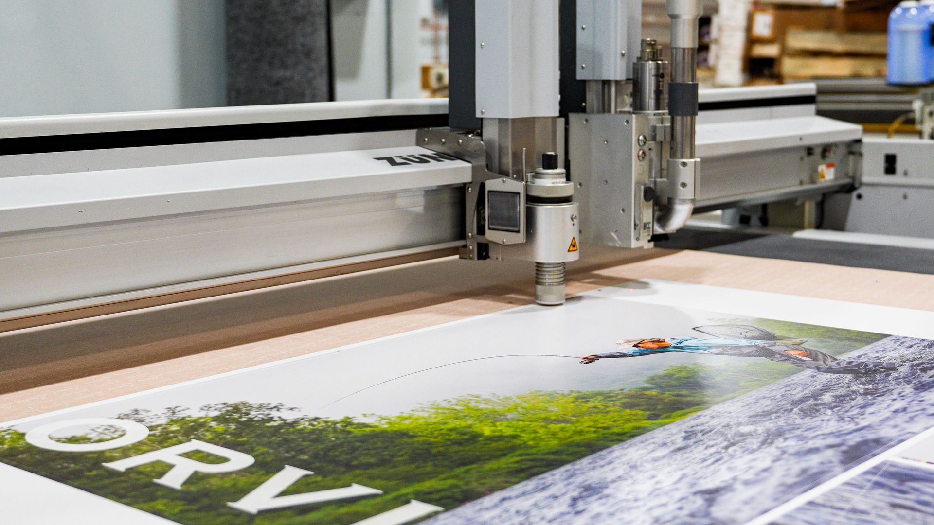 Large-format printer printing a colorful landscape poster on white paper