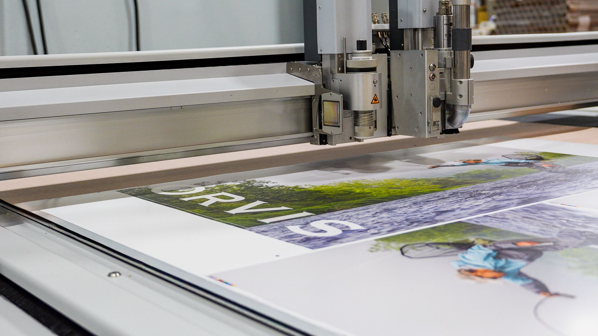 A large format printing machine cutting a printed sign, close up.