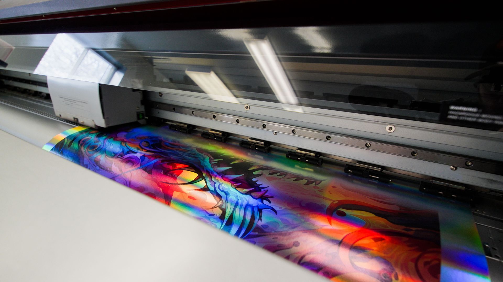Large-format printer printing a vivid rainbow-colored graphic on glossy paper