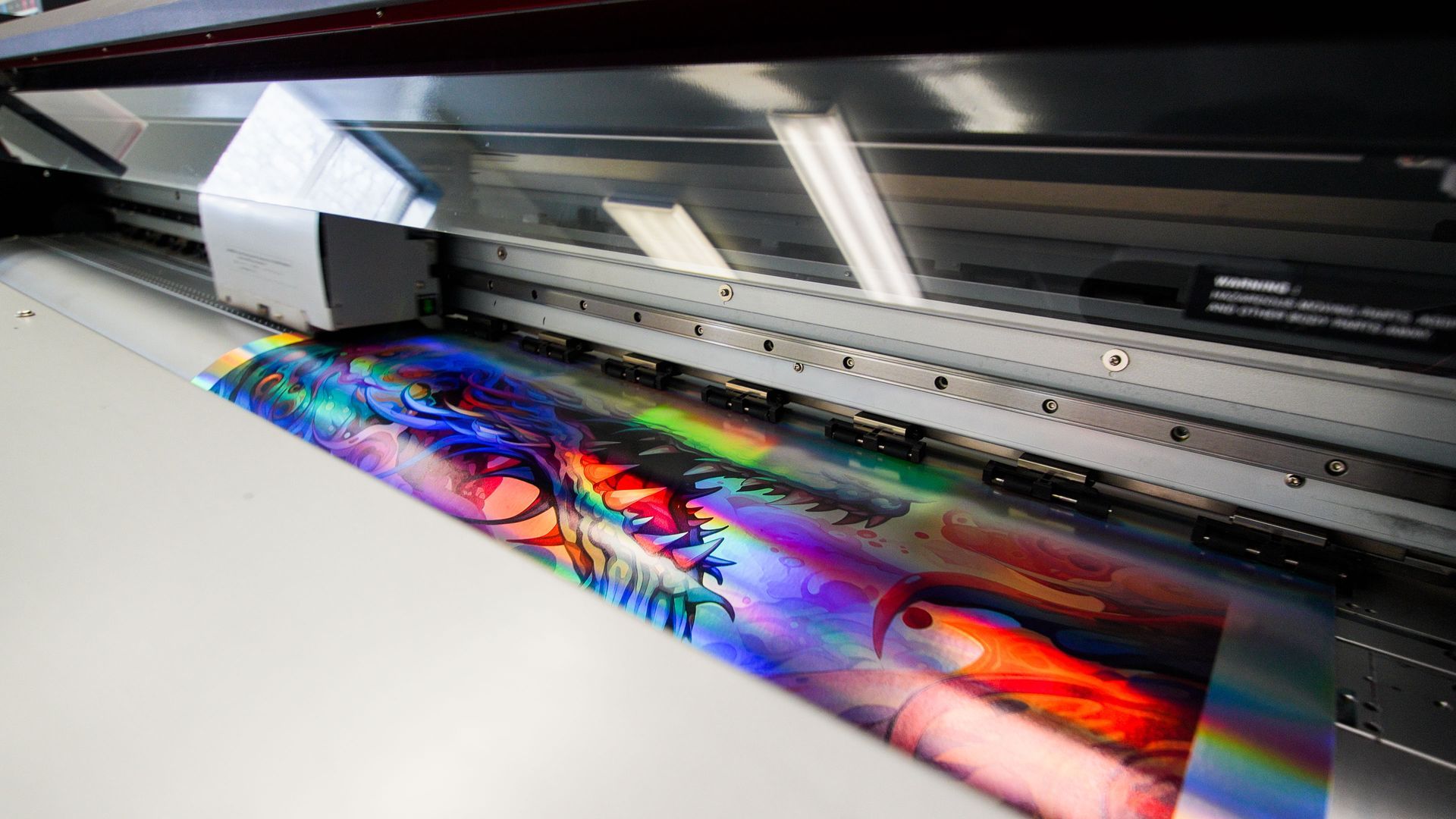 Large-format printer printing a vivid, colorful poster on glossy paper