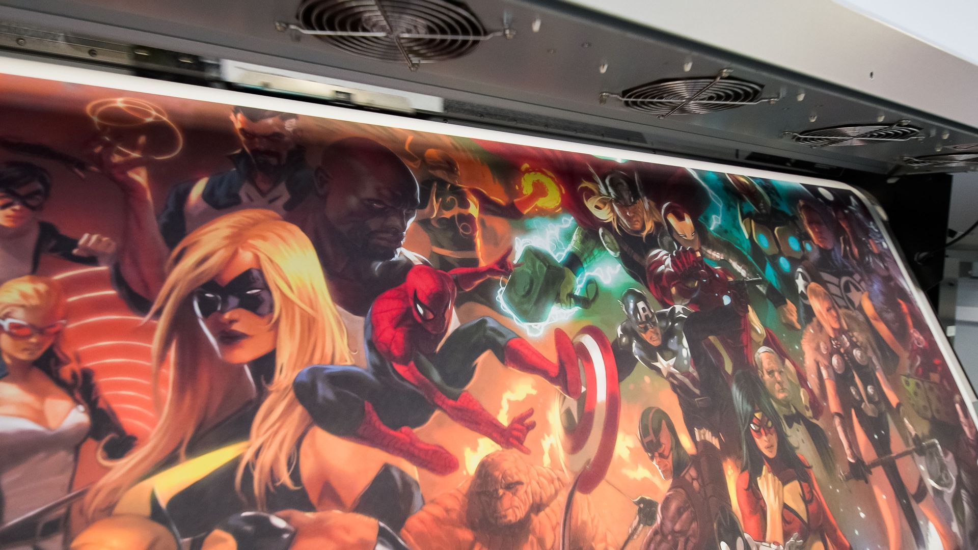 Colorful anime-style mural on a wall beneath ceiling vents, featuring dynamic characters in vivid reds, blues, and oranges