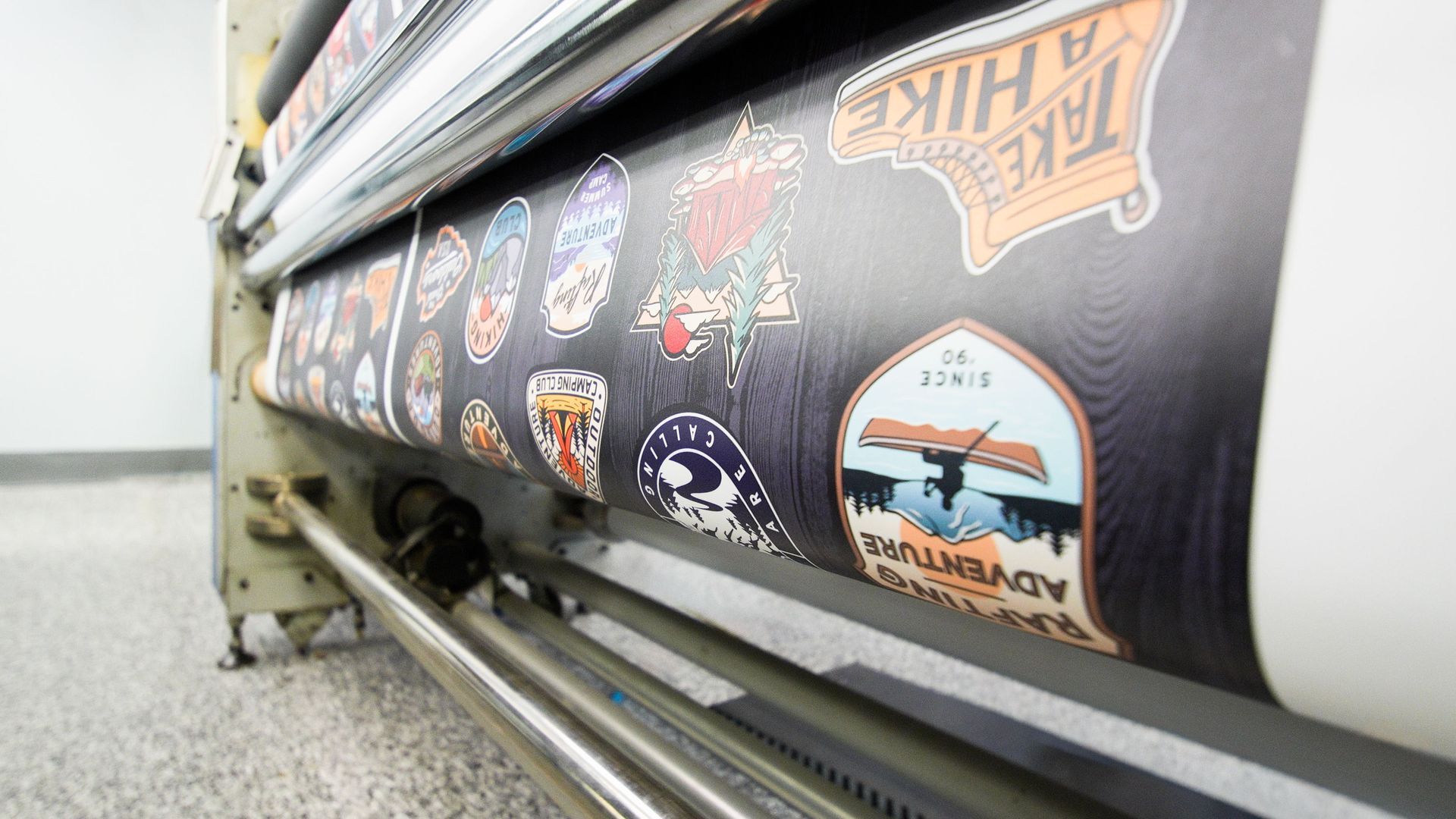 Large printer outputting a roll of sticker decals in a workshop setting