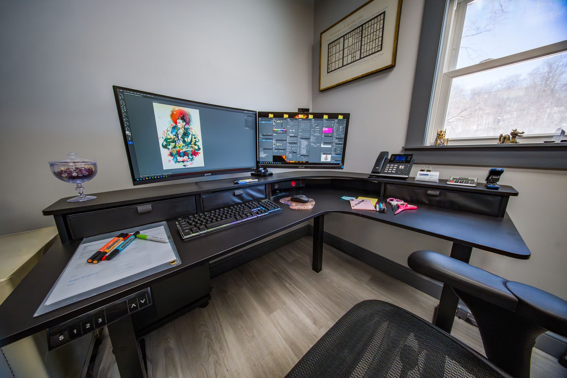 Modern home office with dual monitors, black corner desk, keyboard, drawing tablet, and office chair.