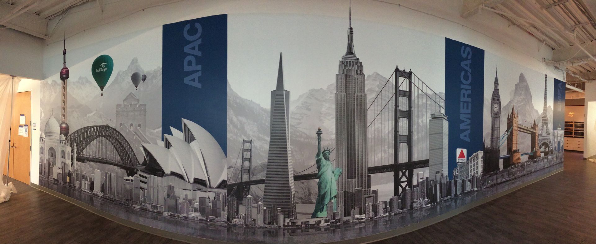 Curved APAC conference wall mural with a city skyline and landmark silhouettes in black, gray, and blue.