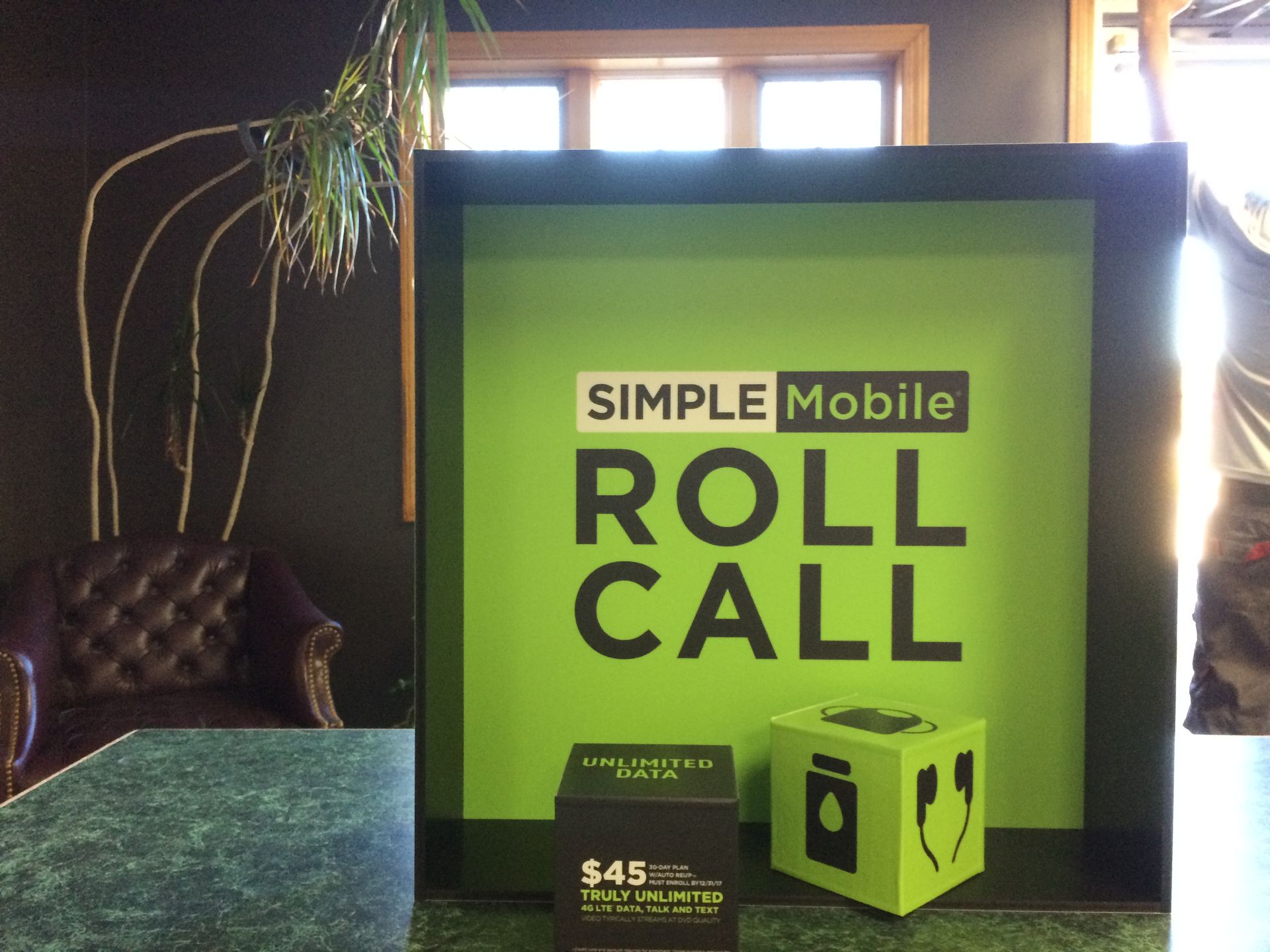 Simple Mobile Roll Call sign with green and black accents, a dark background, and a chair.