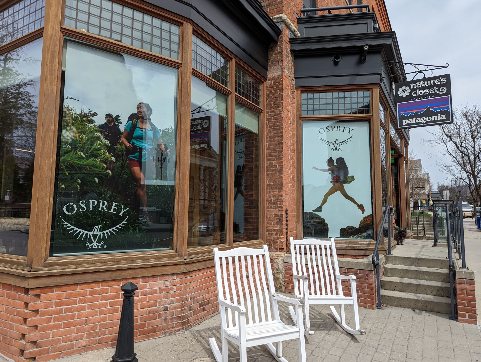 Storefront windows with mannequins and an Osprey logo on a brick sidewalk corner.