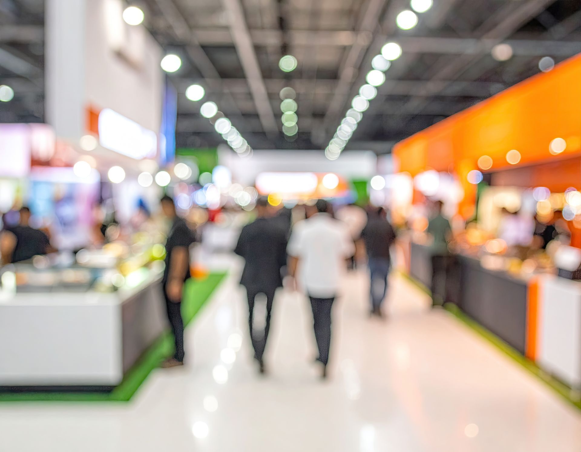 Blurred people walking through a bright trade show aisle with colorful booths on both sides