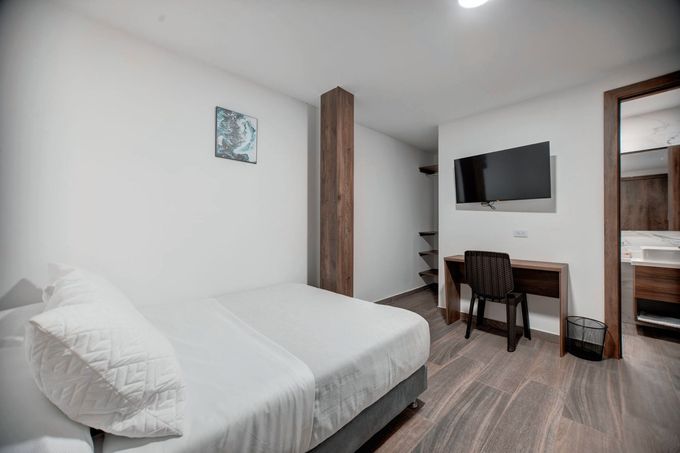 Una habitación de hotel con cama, escritorio, silla y televisión.