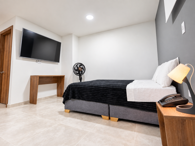 Una habitación de hotel con cama, escritorio, silla y televisión.