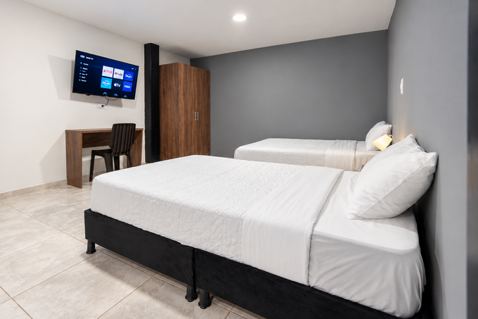 Una habitación de hotel con dos camas y un televisor de pantalla plana