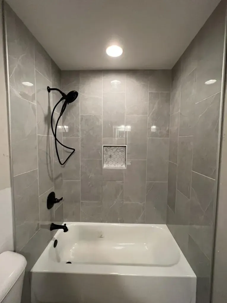 A bathroom with a bathtub , toilet and shower.