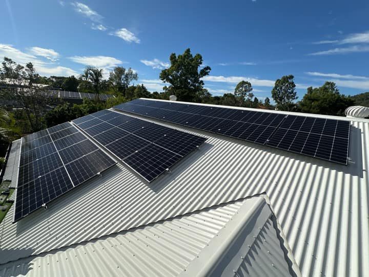 Solar panels installed across multiple roof sections on a white colorbond home in Townsville, surrounded by trees